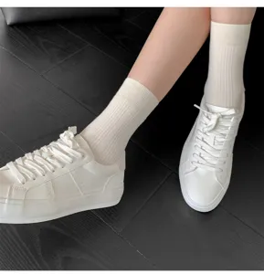 Vue détaillée de chaussettes mi-hautes côtelées blanches pour femmes avec des baskets.
