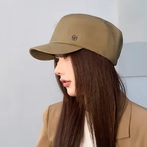 Vintage washed flat top cadet hat detail, stylish khaki newsboy cap with metal badge.