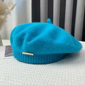 Close-up detail shot of a vibrant blue knitted beret with a stylish metal tag, cozy winter fashion.