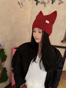 Plano detallado de un gorro de punto rojo con orejas de gato y etiqueta, invierno.