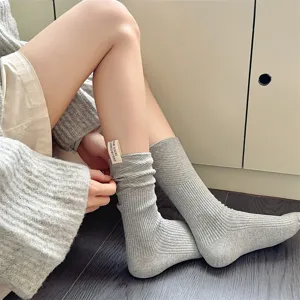 Detailaufnahme gemütlicher grauer Strick-Stulpensocken für Damen mit Stoff-Etikett.