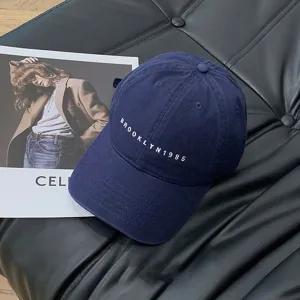 Detailed view of dark blue baseball cap with Brooklyn 1985 embroidery on black leather background.