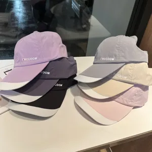 Detailed view of multiple colored quick-drying baseball caps stacked neatly on a white table.