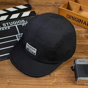 Primer plano detallado de gorra negra de secado rapido con parche de montana en madera.