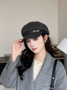 Grey wool newsboy hat detail, featuring black leather strap with white letters for autumn.