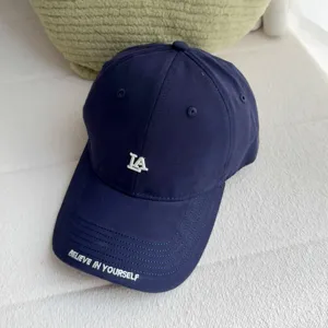 Close-up detail of navy blue baseball cap with embroidered LA logo and brim lettering.
