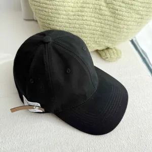 Minimalist black cotton baseball cap with side leather tag, vintage soft top casual dad hat.