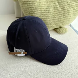 Detail shot of the navy baseball cap featuring side leather tag and soft unstructured crown.