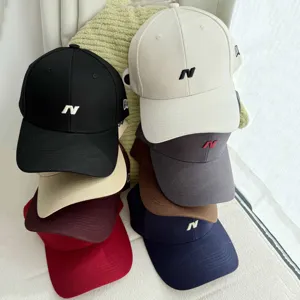 Primer plano de gorras de béisbol coloridas apiladas con detalle de bordado con la letra N.