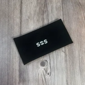 Gedetailleerd shot van zwarte gebreide muts met witte SSS borduursel en fijne textuur.