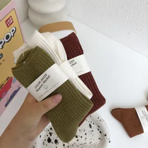 Detail view of minimalist solid color mid-tube cotton socks in Maillard brown and green tones.