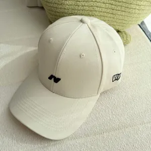 Primer plano detallado de gorra de béisbol beige con bordado frontal y diseño elegante.