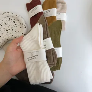 Detail view of Maillard color cotton mid-tube socks with paper belly band packaging.
