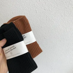 Classic solid color ribbed mid-calf cotton socks in black and brown with paper band detail.