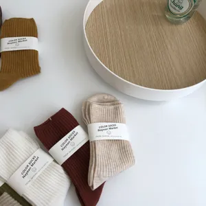 Detail shot of minimalist solid color ribbed cotton mid-tube socks in autumn Maillard tones.