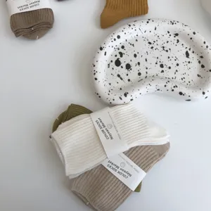 Detailed view of minimalist ribbed cotton socks in neutral earth tones with packaging.