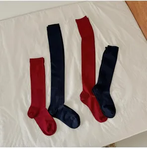 Detail view of soft ribbed wool long socks in red and dark blue displayed on white fabric texture.