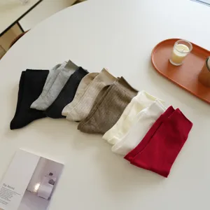 Close-up detail of soft cotton ribbed mid-calf socks in assorted Maillard autumn colors.