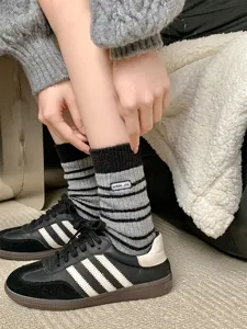 Close-up of woolen striped slouch socks with embroidered logo detail for winter warmth.