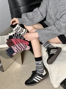 Detailed shot of thick warm striped women's wool-blend slouch socks with cute embroidery.