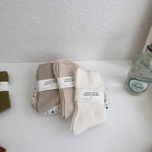 Minimalist solid color mid-tube cotton socks with paper band packaging, comfortable daily wear.