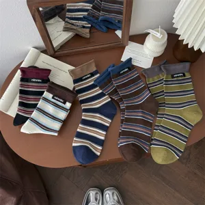 Detailed view of retro striped cotton mid-tube socks with small label on wooden tabletop.