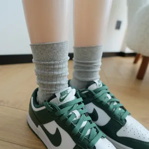 Detail shot of grey ribbed mid-tube stacking socks paired with stylish green sneakers.