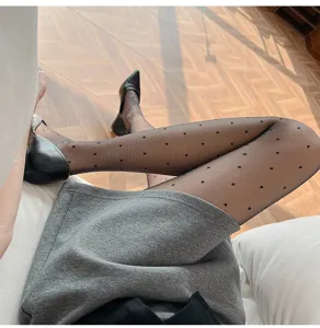 Sheer black pantyhose with cute polka dot pattern, close-up detail shot of legs and shoes.