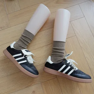 Detail shot of brown cotton crew socks with vertical ribs, styled with sneakers on parquet.