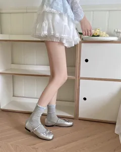 Calcetines grises con volantes combinados con zapatos Mary Jane plateados de estilo dulce.