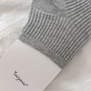 Gros plan sur la chaussette de jambe en tricot côtelé gris avec détail de carte, texture élastique.