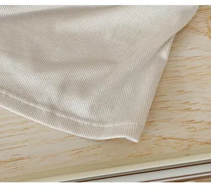 Close-up detail of soft ribbed modal camisole fabric and neat hem stitching texture.