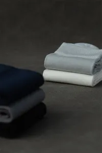 Vue de détail de chaussettes mi-tubes d'affaires pour hommes minces empilées sur fond sombre.