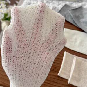 Detailed view of white hollow-out knit leg warmers, ballet style footless socks.