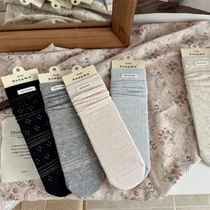 Close-up detail of Japanese hollow knit slouch socks with brand label, soft combed cotton.