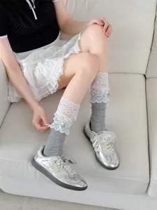 Close-up detail of sweet lolita lace ruffle grey tube socks worn by model on sofa.