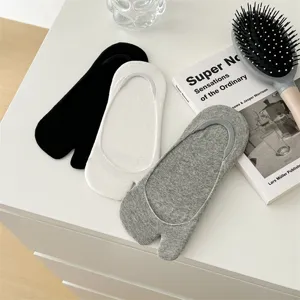 Detail shot of cotton split toe invisible socks in black white grey, flat lay on white table.