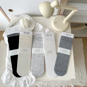 Detail shot of women's hollow lace-trim cotton slouch socks, showcasing fine knit texture and soft cozy lifestyle display on a clean white table.