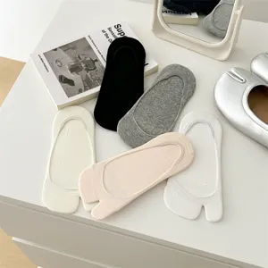 Close-up of cotton split-toe shallow invisible socks in assorted neutral colors on white table.