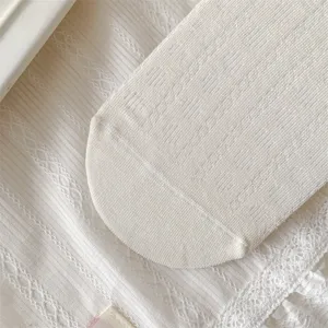 Close up view of white cotton hollow out socks with delicate lace trim and fine knit texture.