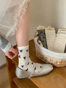 Vista detallada de calcetines de mujer con lazos y diseño calado, con zapatos plateados.