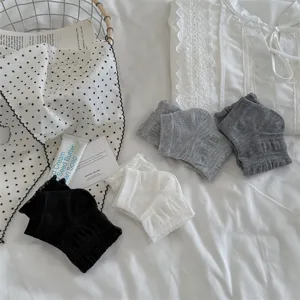 Detail view of cute ruffles socks in black white grey, soft fabric for sweet spring outfits.