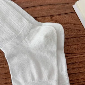 Detail shot of white knitted ribbed socks on wooden background, soft texture, spring style.