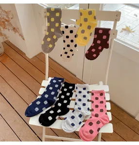 Detailopname van kleurrijke polkadot katoenen sokken netjes uitgestald op een witte stoel.