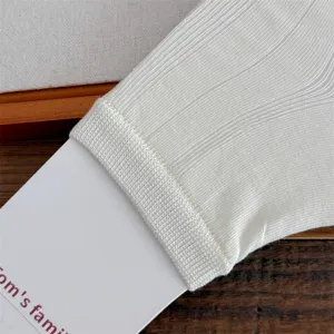 Close up detail of white ribbed knit leg warmer sock showing texture and soft fabric material.