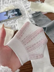 Close up view of white hollow knit stirrup leg warmers showing fine texture and pattern.