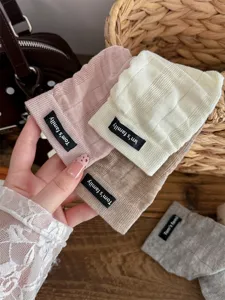 Detail shot of ribbed knit stirrup leg warmers featuring stylish fabric labels, cozy texture.