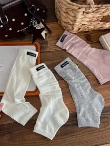 Detail shot of women ballet stirrup leg warmers, ribbed knit slouch socks with label.
