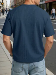 Back view detail of men's dark blue waffle knit short sleeve raglan t-shirt on street.