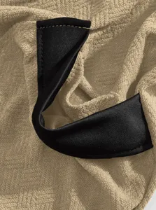Detailopname van badjas van badstof, zachte stof met stevige zwarte ophanglus en stiksels.